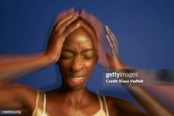 multiple exposure of terrified young woman with head in hands - mal de tête photos et images de collection