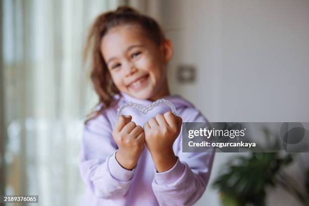 young smiling little girl holding braces over white background studio, dental healthcare and orthodontic concept. - aparelho dentário imagens e fotografias de stock