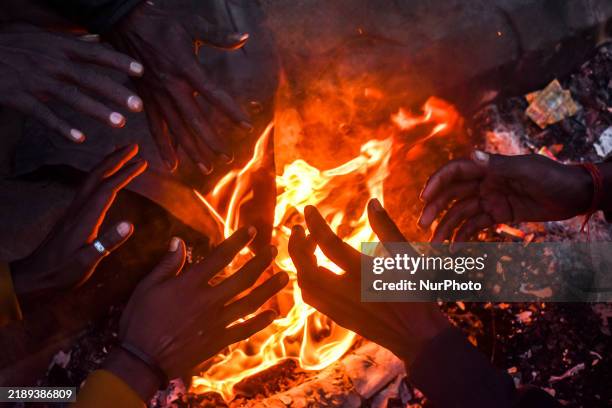 Men warm themselves by a fire on a cold winter morning in Kolkata, India, on December 15, 2024.