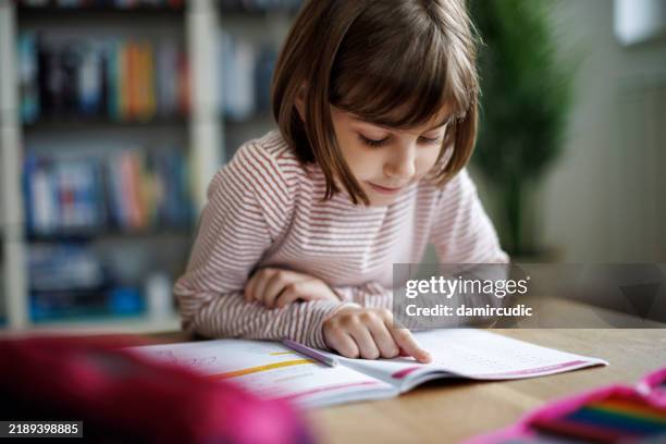 cute little girl reading her book carefully at the table - endast en flicka bildbanksfoton och bilder
