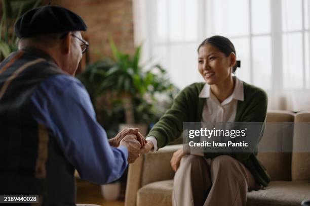 compassionate interaction between elderly man and caregiver in room with natural light - words of support and encouragement stock pictures, royalty-free photos & images