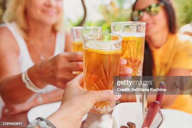 hands holding glasses of iced tea together - limonade stockfoto's en -beelden