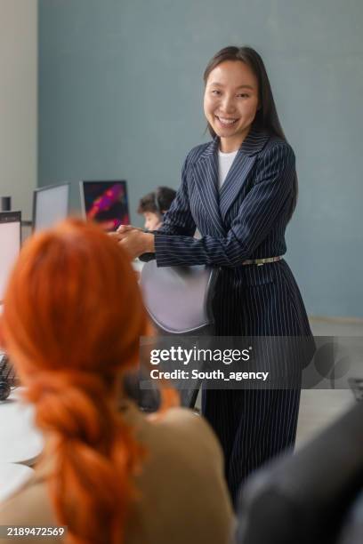 professional businesswoman interacting with colleagues in a modern office setting - dress code stock pictures, royalty-free photos & images
