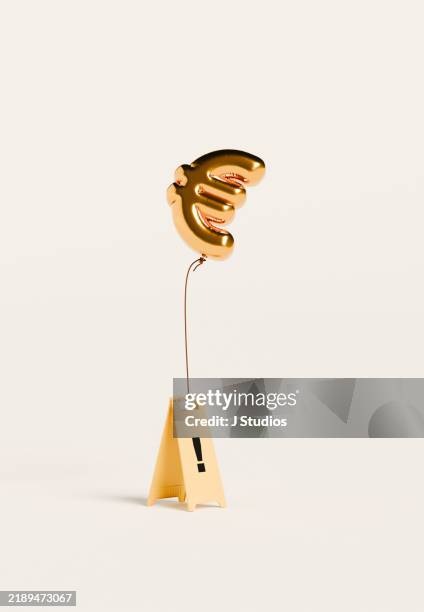 euro sign balloon hovering above caution sign - euro symbol stock-fotos und bilder