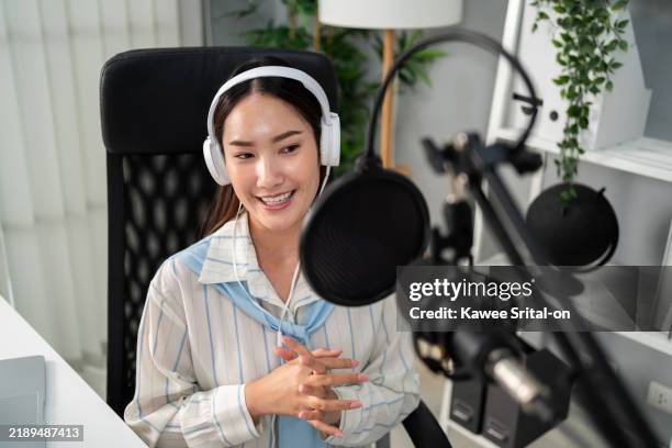 asian podcaster in headphones using microphone broadcasting in studio. attractive female content creator blogger recording podcast voice over radio conversation for social media channel in the office. - content creation stock pictures, royalty-free photos & images