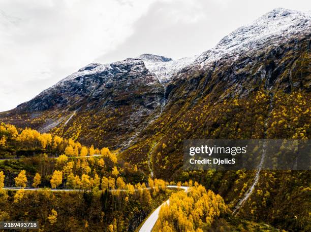 aerial view of stunning high mountains and winding road in norway on autumn day - dramatic landscape stock pictures, royalty-free photos & images