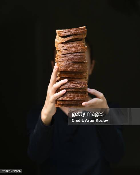 wheat rye toast, dark bread slices in hands. stack of sliced homemade bread bricks. breakfast, sandwich, snack. bakery, vegan baked goods with crust. stale dry whole wheat bread, rusks. flour product - low fiber food stock pictures, royalty-free photos & images