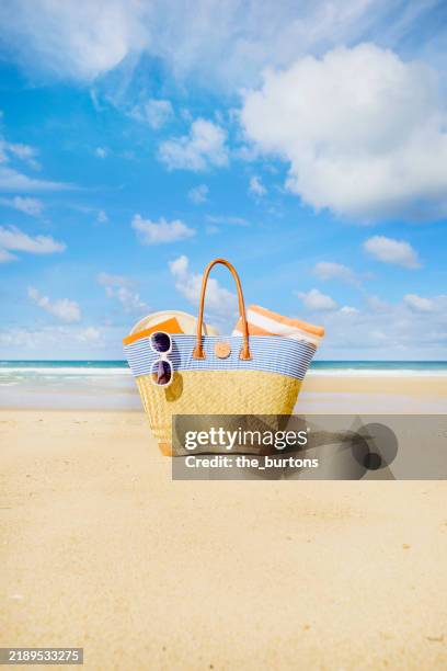 beach bag with towel, book and sunglasses at beach and sea against blue sky - beach bag stock pictures, royalty-free photos & images
