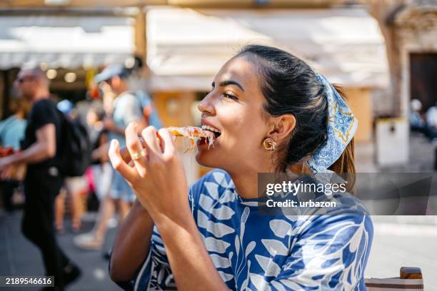 young brazilian woman eating a slice of pizza in a restaurant outdoors in taormina in sicily - ionian sea stock pictures, royalty-free photos & images