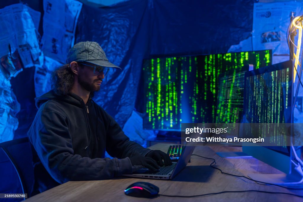 Hacker at Work in Dimly Lit Tech Room with Multiple Screens
