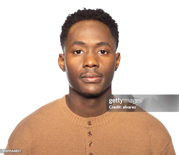 studio portrait of a serious young man of latin american ethnicity in a brown sweater - frontaal stockfoto's en -beelden