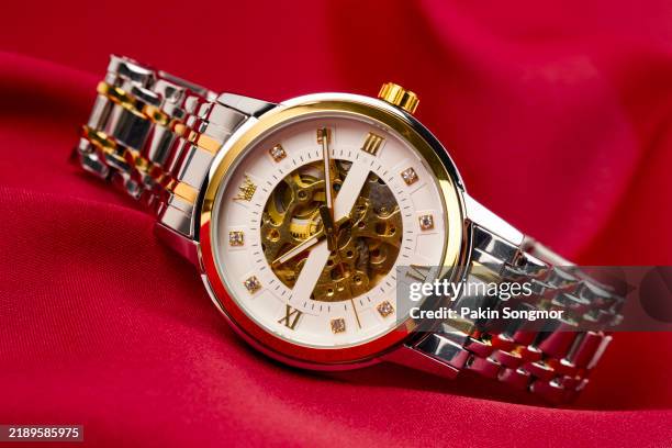 close up product shot of a precious silver metal with diamonds womens chronograph wrist watch with a black design placed isolated inside a studio with red background. - colección de la moda fotografías e imágenes de stock