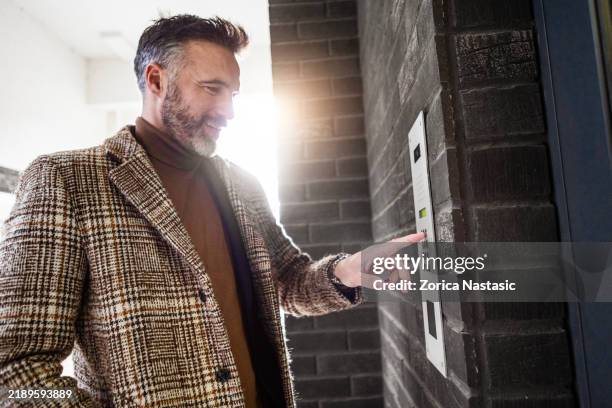 man pressing apartment intercom to call inside - hand ringing bell stock pictures, royalty-free photos & images