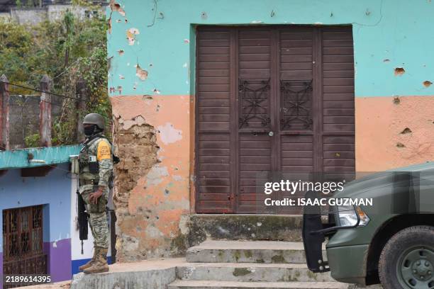 An army soldier stands guard next to a house with bullet holes after clashes between armed groups in Pantelho, Chiapas state, Mexico on December 15,...