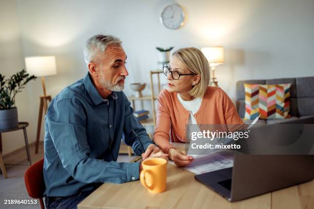 couple d’âge mûr dépassant les factures à la maison - adulte dâge mûr photos et images de collection
