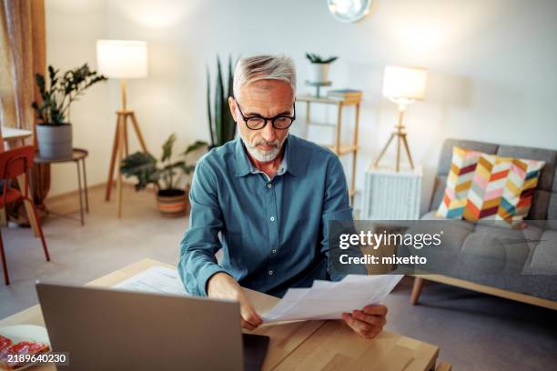 mature man going over bills at home - bank statement stock pictures, royalty-free photos & images