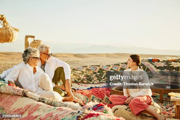 wide shot senior couple relaxing with adult daughter at desert camp - glamping stock-fotos und bilder