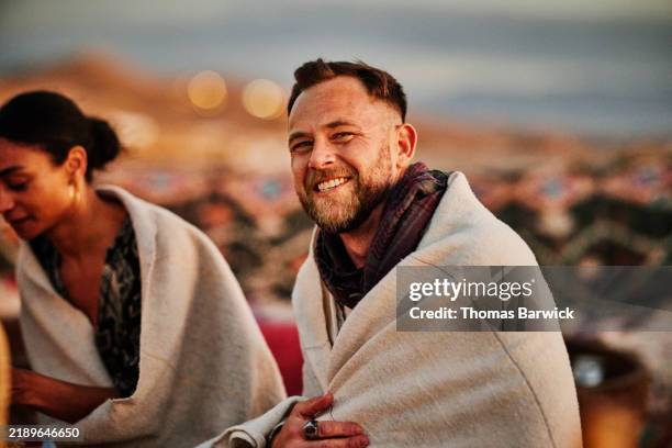 medium shot man smiling at camera while outdoors at desert camp at sunset - north africa stock pictures, royalty-free photos & images