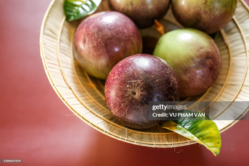 Star apple tropical fruits inside cone shaped straw hat