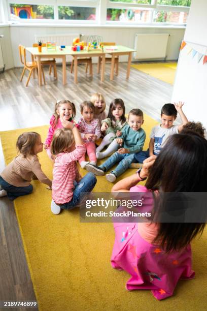 children sit on the floor and listen to the animator in the playroom - child care stock pictures, royalty-free photos & images