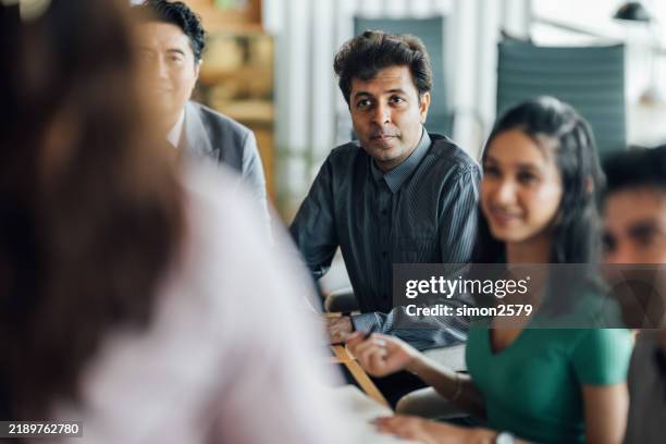 colleagues thriving in a modern meeting room as they work toward shared goals - malaysian people stock pictures, royalty-free photos & images