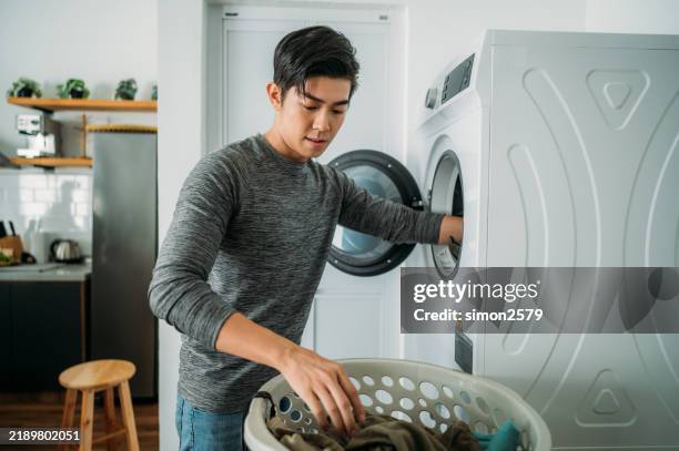 everyday moments: a young chinese man doing laundry - droger stockfoto's en -beelden