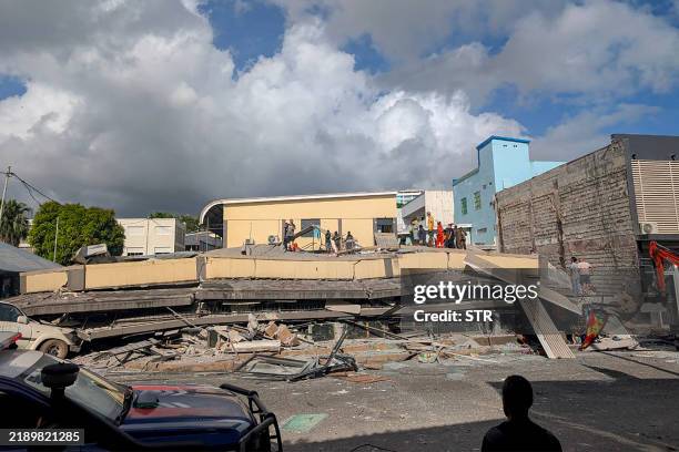 Rescue workers are seen at the site of a collapsed building after a powerful earthquake struck Port Vila, the capital city of Vanuatu, on December...