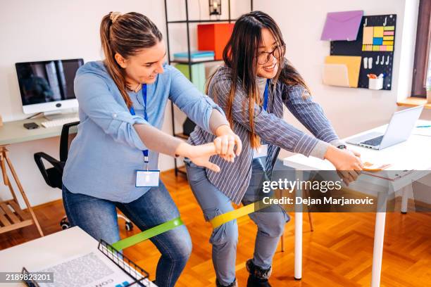 colleagues exercising together while on a break in office using rubber band - elastiekje stockfoto's en -beelden
