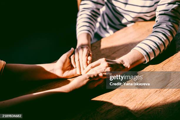 two unrecognizable persons holding each other's hands. emotional support during hard times - menselijke relaties stockfoto's en -beelden