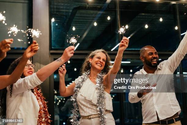 friends celebrating new year's eve with sparklers - business party stockfoto's en -beelden