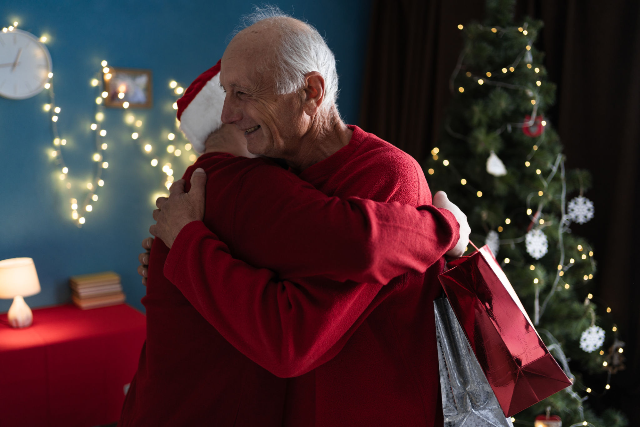 An elderly father hugs his son who came to visit him on Christmas or New Year with gifts. The concept of family and holidays An elderly father hugs his son who came to visit him on Christmas or New Year with gifts. The concept of family and holidays