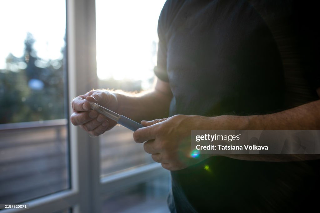 Close-up of hands administering semaglutide injection. Focus on the medical device. Weight loss treatment in progress.