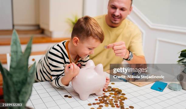 father and son piggy bank - pocket money stock pictures, royalty-free photos & images