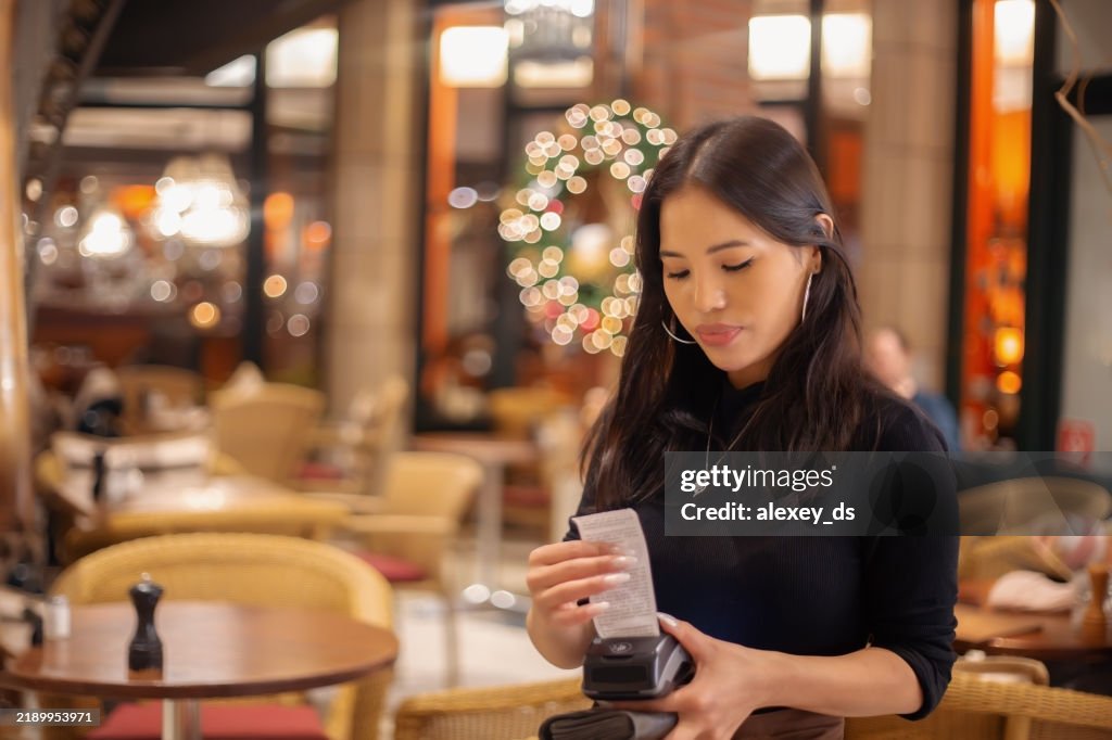 Young waitress holding a bill and a credit card machine in a restaurant