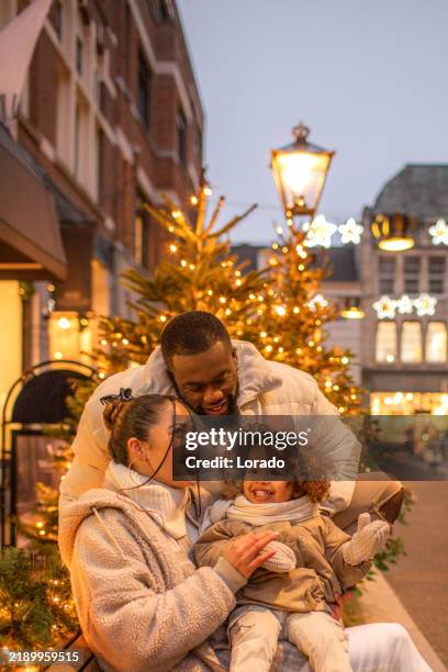 lifestyle shoot of a beautiful mixed race family on a christmas street - christmas travel stock pictures, royalty-free photos & images