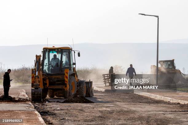 Bulldozers move during ongoing construction work at the settlement of Katzrin in the Israeli-annexed Golan Heights on December 17, 2024. At the end...