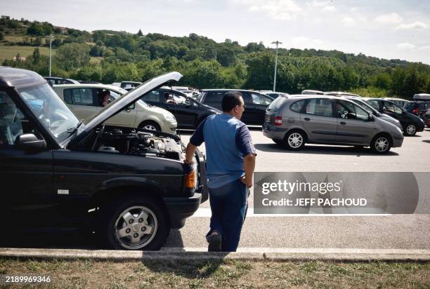 Une personne patiente près de son véhicule en panne, le 11 juillet 2009 près de la barrière de péage de Vienne sur l'autoroute A7 alors que des...