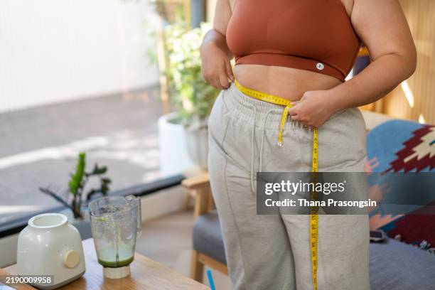 close up overweight woman measuring her hip with tape measure - obesidad fotografías e imágenes de stock