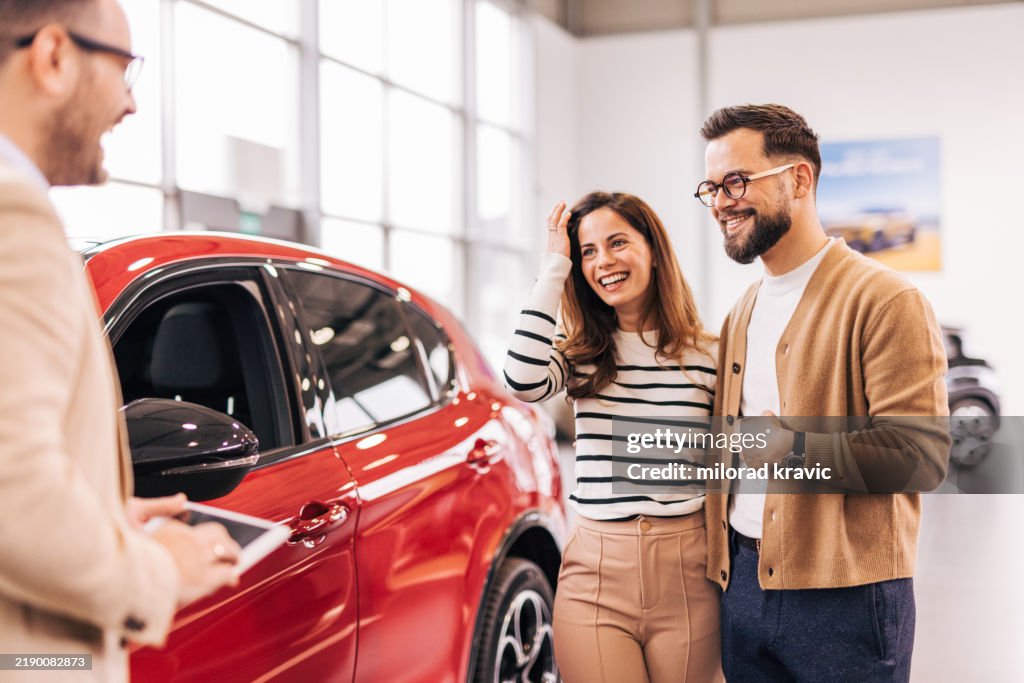Car salesman discussing contract with couple