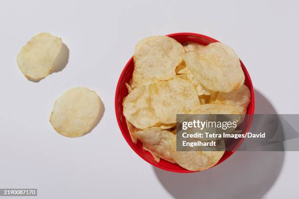 overhead view of potato chips in bowl on white background - crisps stock pictures, royalty-free photos & images