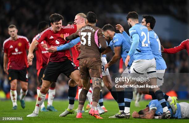 Harry Maguire of Manchester United and Erling Haaland of Manchester City clash as Kyle Walker of Manchester City reacts on the floor following an...