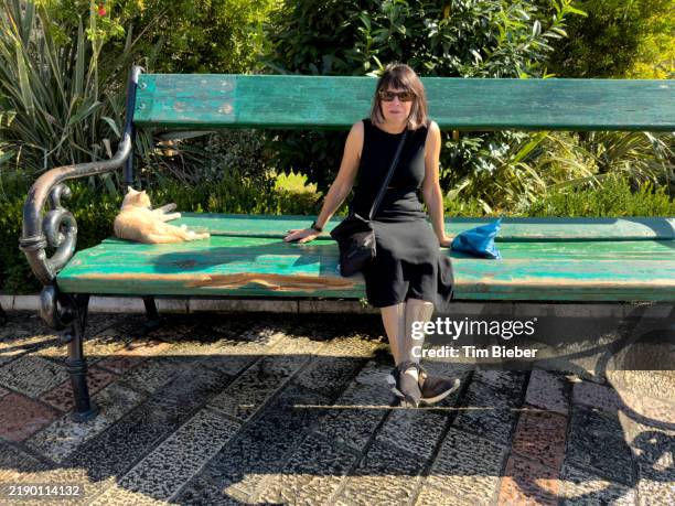 woman sitting on oversized bench - funny people stockfoto's en -beelden