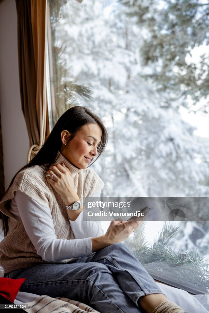 Beautiful woman relaxing by the window in forest cabin