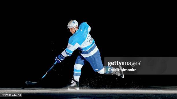 focused ice hockey team captain performing a powerful one-timer - ice hockey player stock pictures, royalty-free photos & images