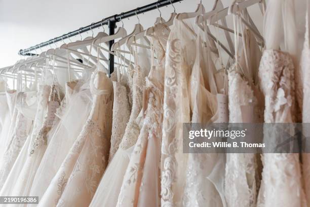 clothing rail displaying beautiful and intricate wedding dresses - trouwjurk stockfoto's en -beelden