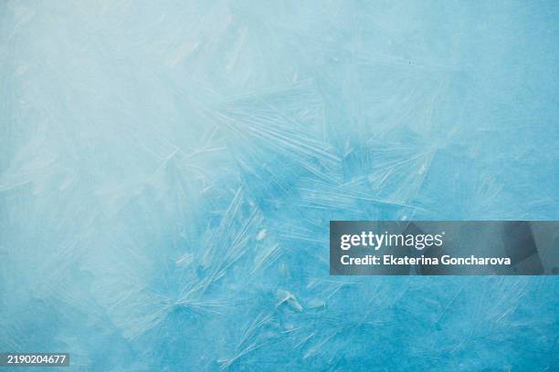 ice crystals creating beautiful frozen patterns on a window in winter - ice stock-fotos und bilder
