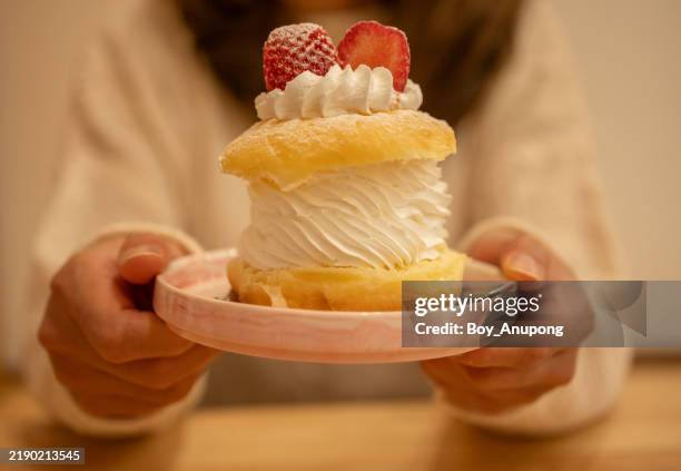 cropped shot view of woman holding a strawberry choux cream before eating. - custard stock pictures, royalty-free photos & images