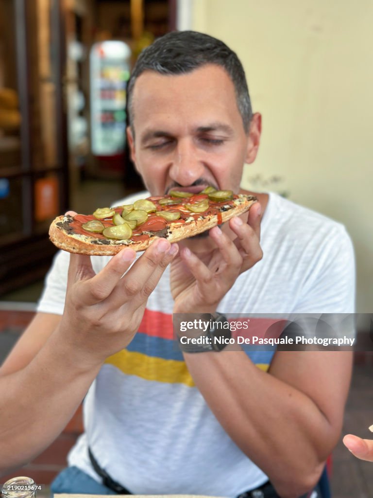 Front view of man eating tipical polish zapiekanka toasted baguette