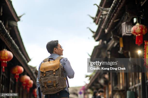 asian chinese male tourist backpacker at ancient town of lijiang , yunnan province , china - yunnan province stock pictures, royalty-free photos & images