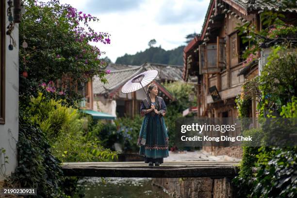 asian chinese female tourist holding umbrella with traditional clothing at ancient town of lijiang , yunnan province , china - yunnan province stock pictures, royalty-free photos & images